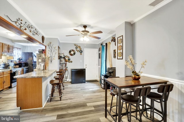 kitchen with stainless steel appliances, a breakfast bar area, light wood-type flooring, and kitchen peninsula