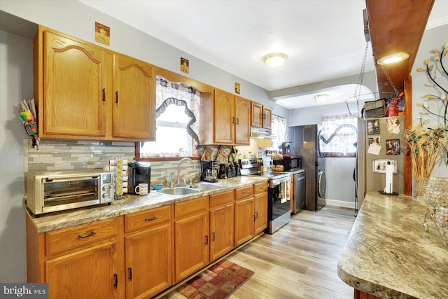 kitchen featuring tasteful backsplash, sink, light hardwood / wood-style flooring, and appliances with stainless steel finishes