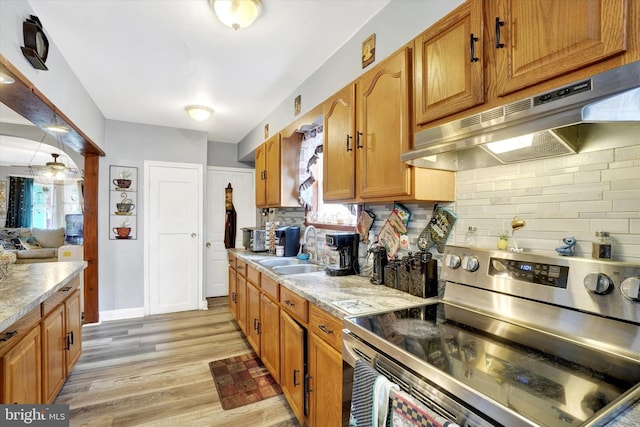 kitchen with tasteful backsplash, sink, light hardwood / wood-style flooring, and stainless steel range with electric stovetop