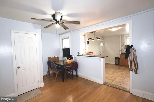 kitchen featuring baseboards, light wood-style floors, dark countertops, and pendant lighting