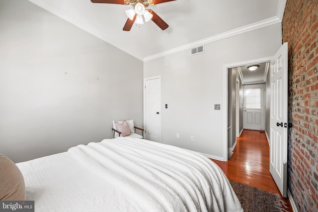 bedroom with hardwood / wood-style floors, ceiling fan, crown molding, and brick wall