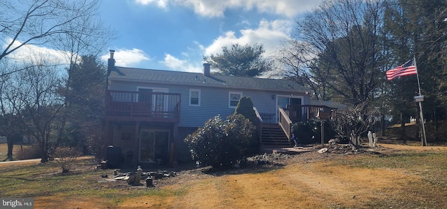 rear view of property featuring a lawn and a deck