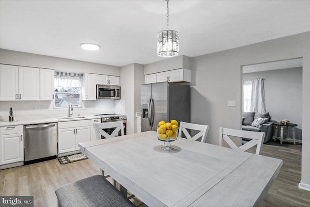 interior space featuring sink, decorative light fixtures, white cabinets, and appliances with stainless steel finishes