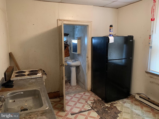 kitchen featuring black refrigerator, sink, a drop ceiling, and baseboard heating