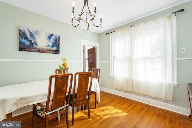 dining area with wood-type flooring and a chandelier