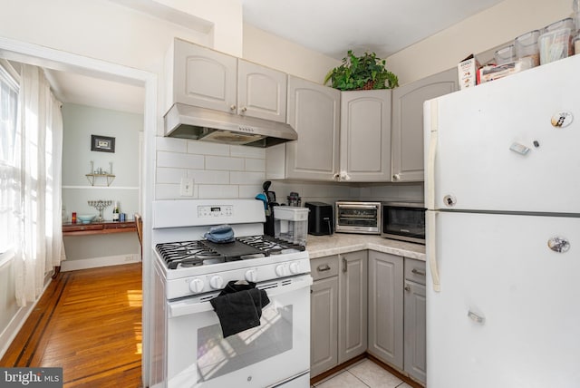 kitchen featuring gray cabinets, tasteful backsplash, white appliances, and light hardwood / wood-style flooring