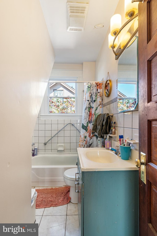 bathroom with plenty of natural light, tile patterned flooring, vanity, and tile walls