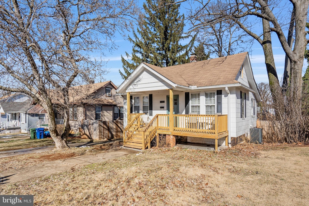 bungalow featuring covered porch, a front lawn, and central air condition unit