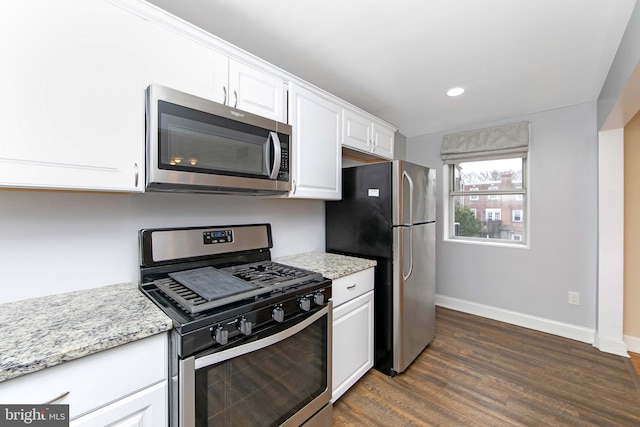 kitchen featuring dark hardwood / wood-style floors, appliances with stainless steel finishes, white cabinets, and light stone countertops