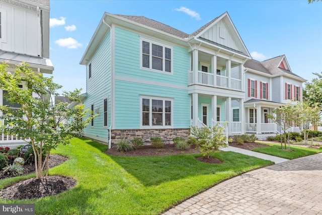 view of front of property featuring a porch, a balcony, and a front yard