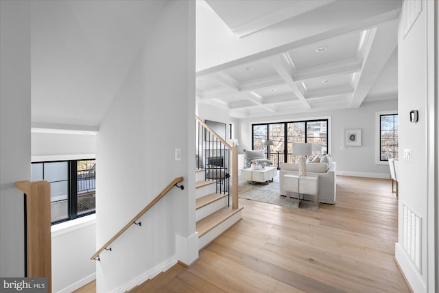 stairs with beamed ceiling, ornamental molding, coffered ceiling, and hardwood / wood-style floors