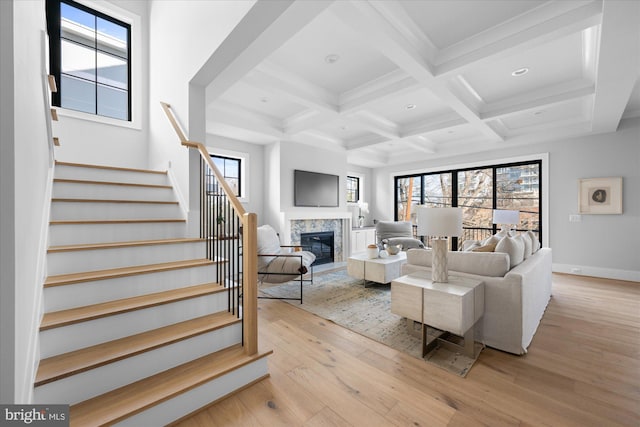 living room featuring beamed ceiling, plenty of natural light, coffered ceiling, and light hardwood / wood-style floors