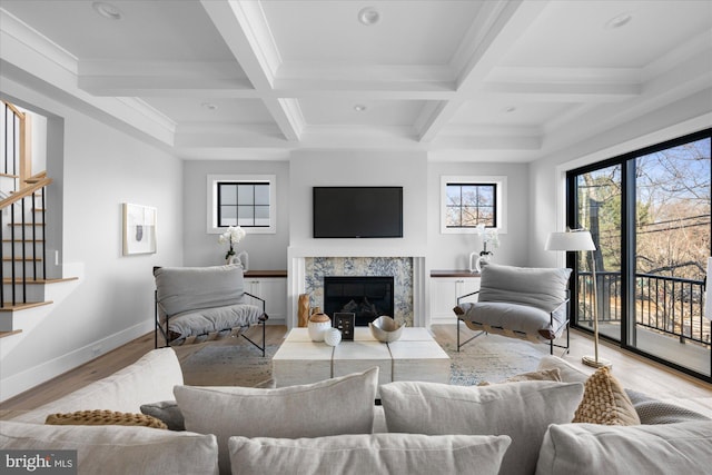 living room with beamed ceiling, coffered ceiling, a fireplace, and light hardwood / wood-style floors