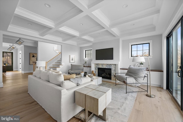 living room featuring beamed ceiling, plenty of natural light, and light hardwood / wood-style flooring