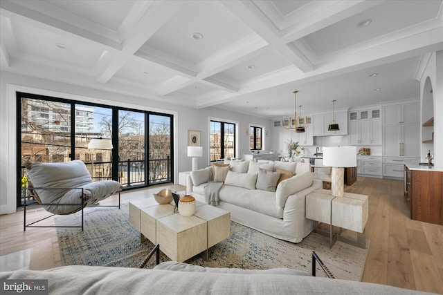 living room featuring coffered ceiling, beam ceiling, crown molding, and light wood-type flooring