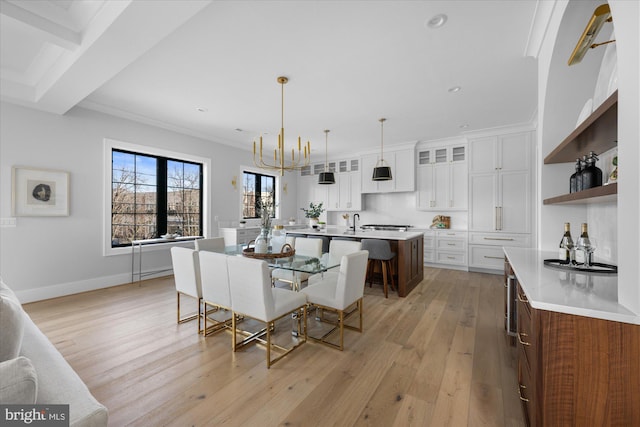 dining space with crown molding, sink, an inviting chandelier, and light hardwood / wood-style floors