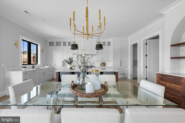 dining room featuring ornamental molding, sink, an inviting chandelier, and light hardwood / wood-style floors