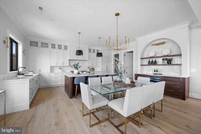 dining area with ornamental molding, a notable chandelier, and light hardwood / wood-style floors