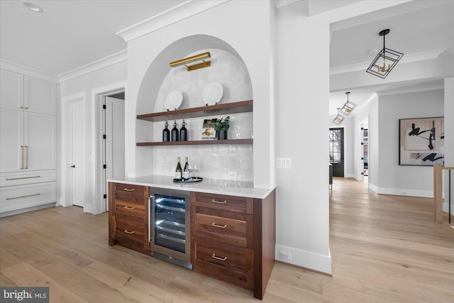 bar featuring crown molding, white cabinetry, wine cooler, decorative light fixtures, and light wood-type flooring