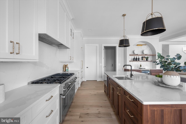 kitchen featuring decorative light fixtures, white cabinetry, sink, stainless steel range, and light stone counters