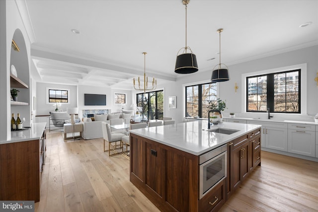 kitchen featuring hanging light fixtures, sink, a kitchen island with sink, and stainless steel microwave