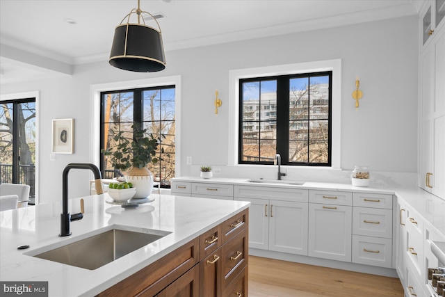 kitchen featuring light stone countertops, sink, light hardwood / wood-style flooring, and white cabinets