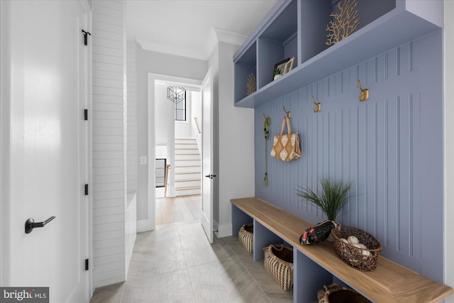 mudroom with crown molding and light tile patterned flooring