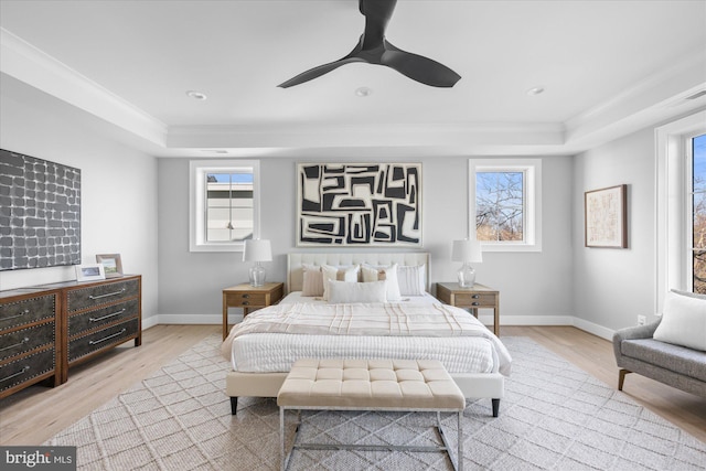 bedroom featuring a raised ceiling, crown molding, ceiling fan, and light hardwood / wood-style floors