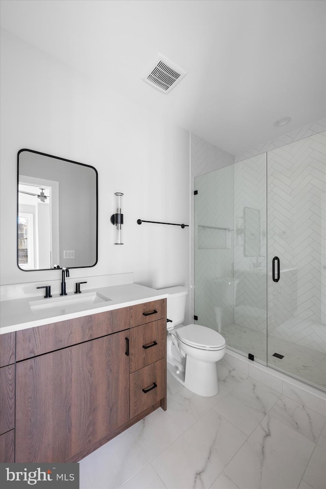 bathroom featuring vanity, a shower with shower door, and toilet