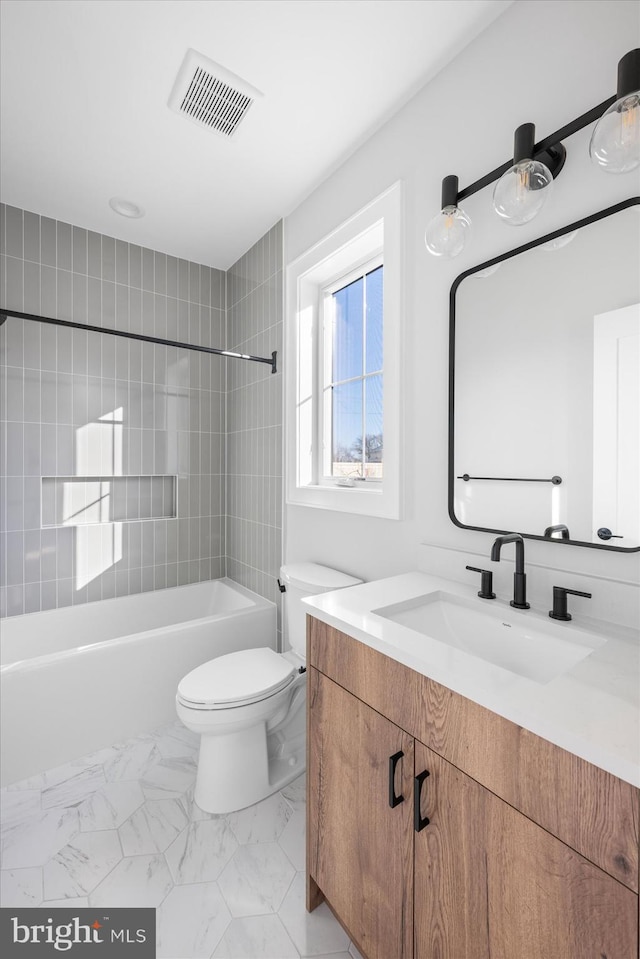 full bathroom featuring tiled shower / bath, vanity, and toilet