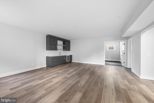 unfurnished living room featuring indoor bar and light hardwood / wood-style flooring