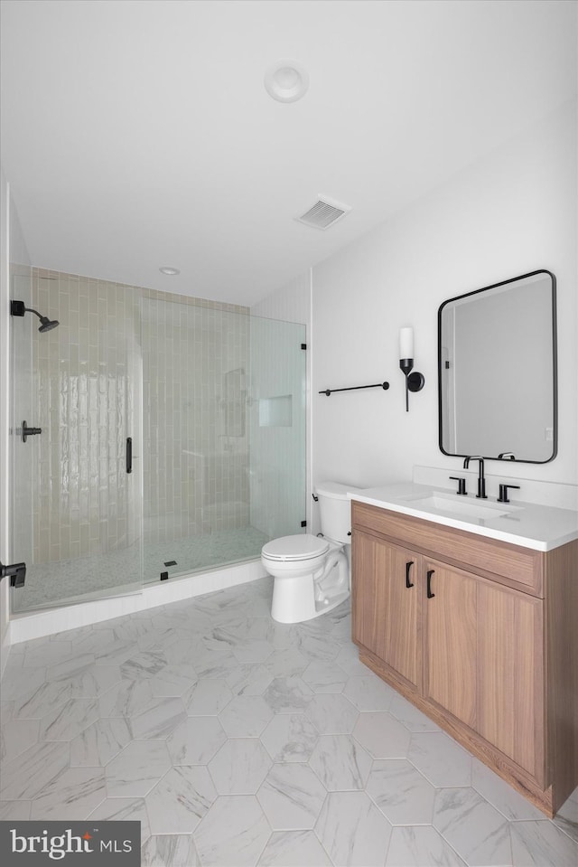 bathroom featuring vanity, a shower with shower door, and toilet