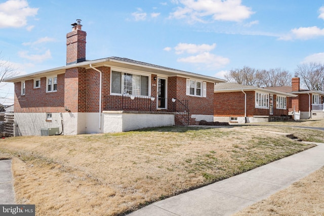 ranch-style home featuring a front yard, brick siding, and a chimney