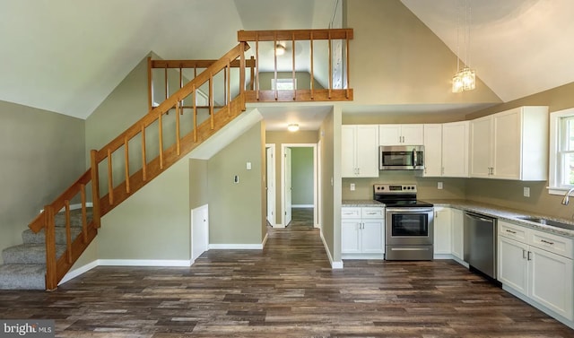 kitchen featuring white cabinetry, appliances with stainless steel finishes, hanging light fixtures, and light stone counters