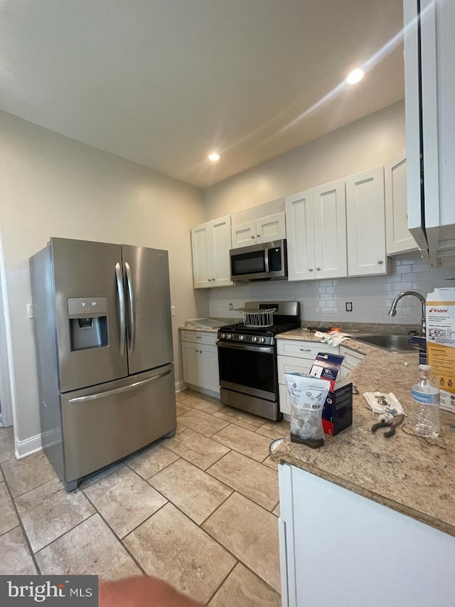 kitchen with sink, white cabinetry, light stone counters, appliances with stainless steel finishes, and decorative backsplash