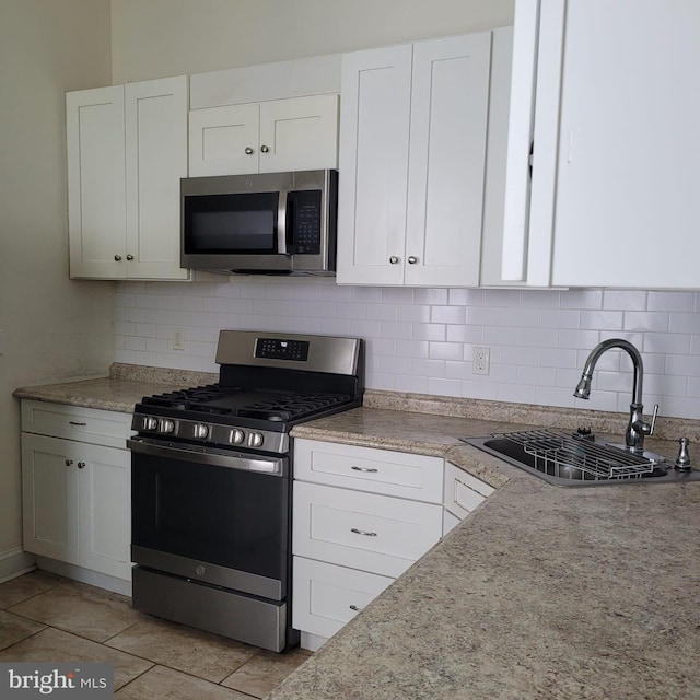 kitchen featuring sink, white cabinetry, backsplash, stainless steel appliances, and light stone countertops