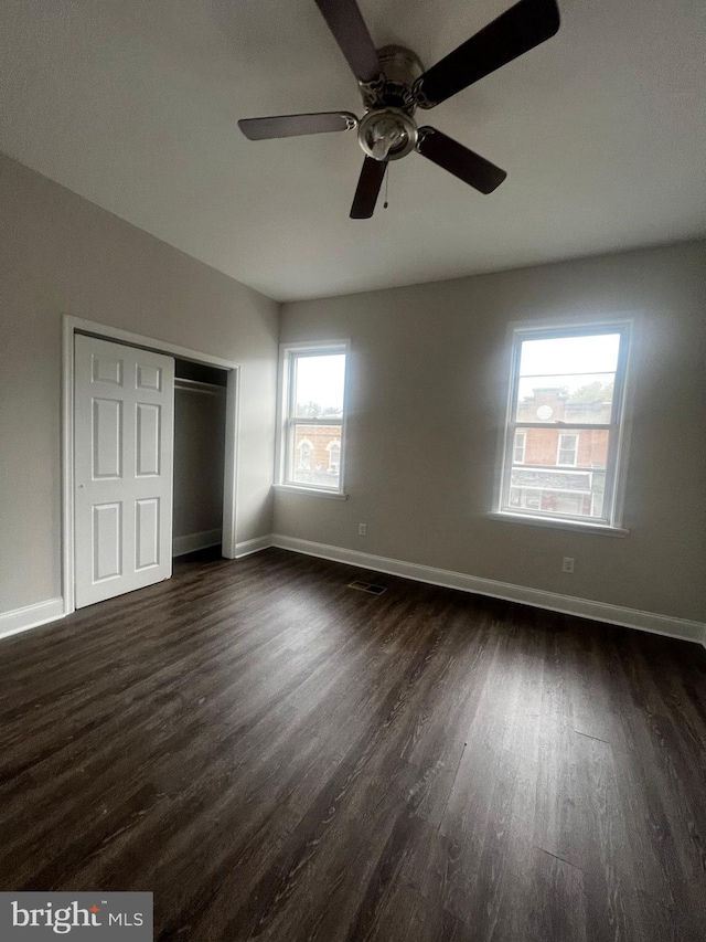 unfurnished bedroom with ceiling fan, dark hardwood / wood-style flooring, and a closet