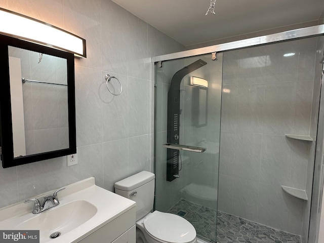 bathroom featuring vanity, toilet, a shower with shower door, and tile walls