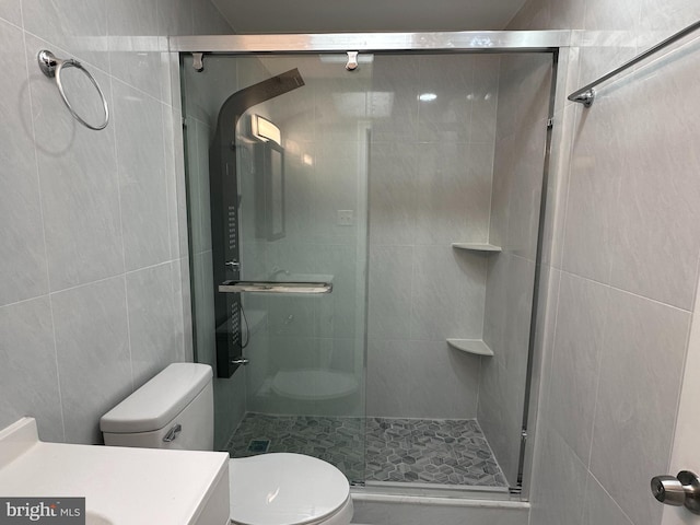 bathroom with an enclosed shower, vanity, tile walls, and toilet