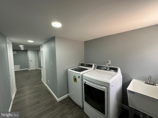 washroom with washing machine and dryer, sink, and dark wood-type flooring