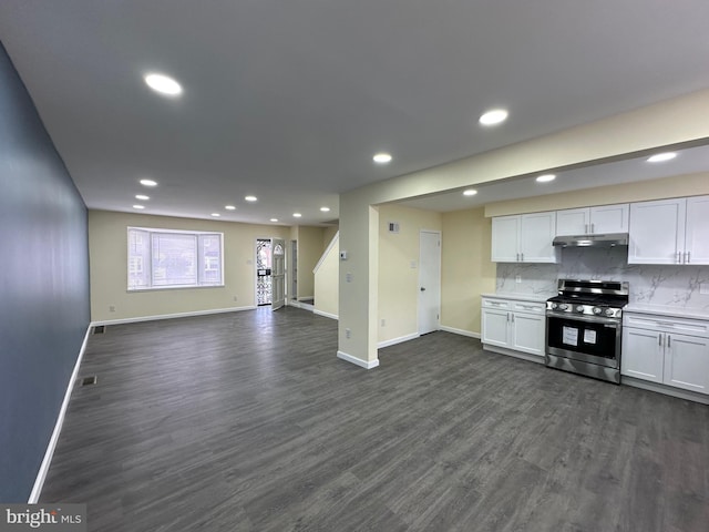 kitchen featuring stainless steel gas range oven, dark wood-type flooring, white cabinets, and backsplash