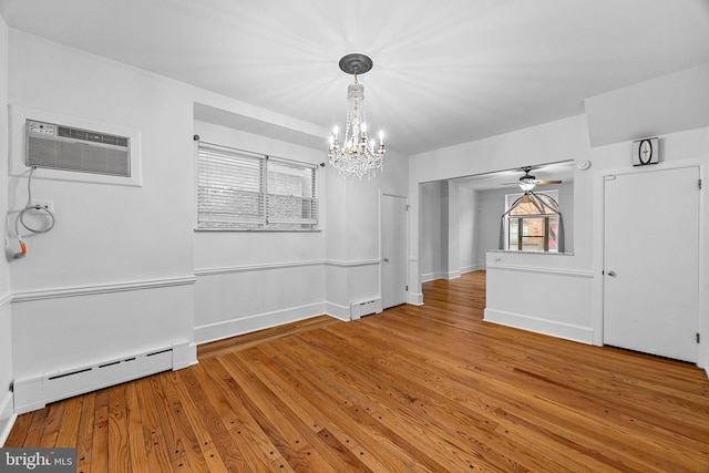 unfurnished dining area featuring hardwood / wood-style flooring, ceiling fan with notable chandelier, an AC wall unit, and baseboard heating