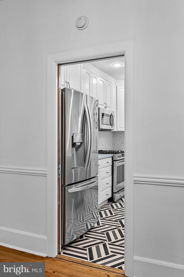 interior details featuring stainless steel appliances, white cabinets, and backsplash