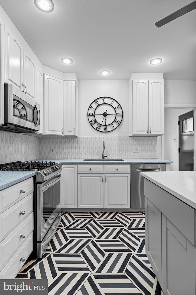 kitchen featuring backsplash, appliances with stainless steel finishes, sink, and white cabinets