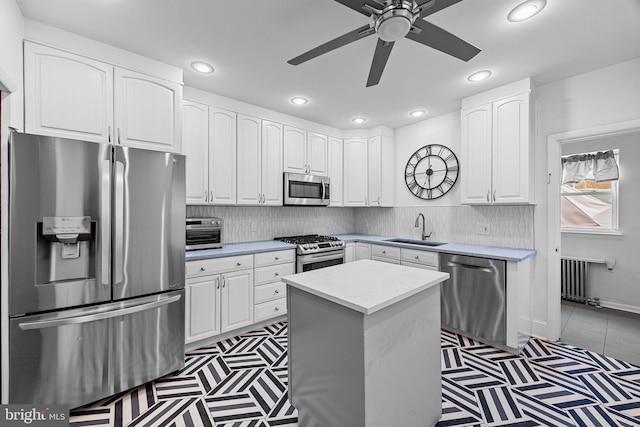 kitchen featuring appliances with stainless steel finishes, sink, a kitchen island, and white cabinets