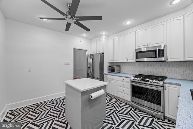 kitchen with appliances with stainless steel finishes, backsplash, white cabinets, and light stone counters