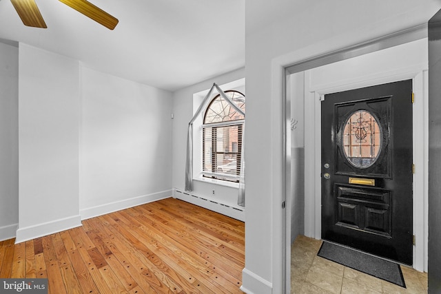 foyer entrance featuring baseboard heating, ceiling fan, and light wood-type flooring