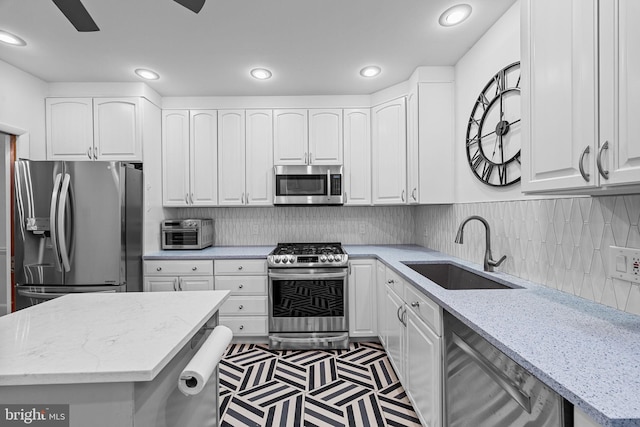 kitchen featuring white cabinetry, sink, stainless steel appliances, and light stone countertops