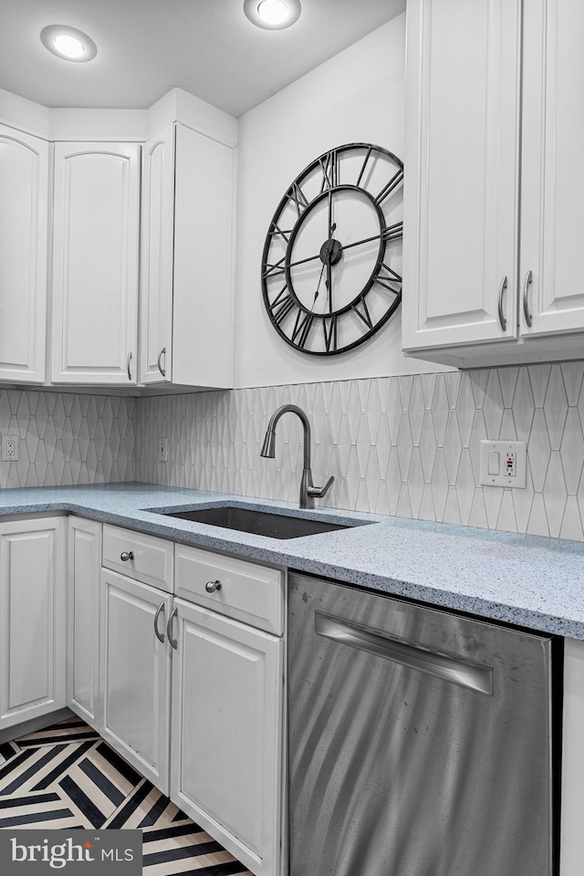 kitchen featuring dishwasher, sink, white cabinets, decorative backsplash, and light stone counters