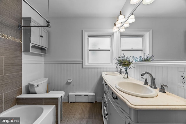 bathroom with baseboard heating, vanity, toilet, and a bathtub